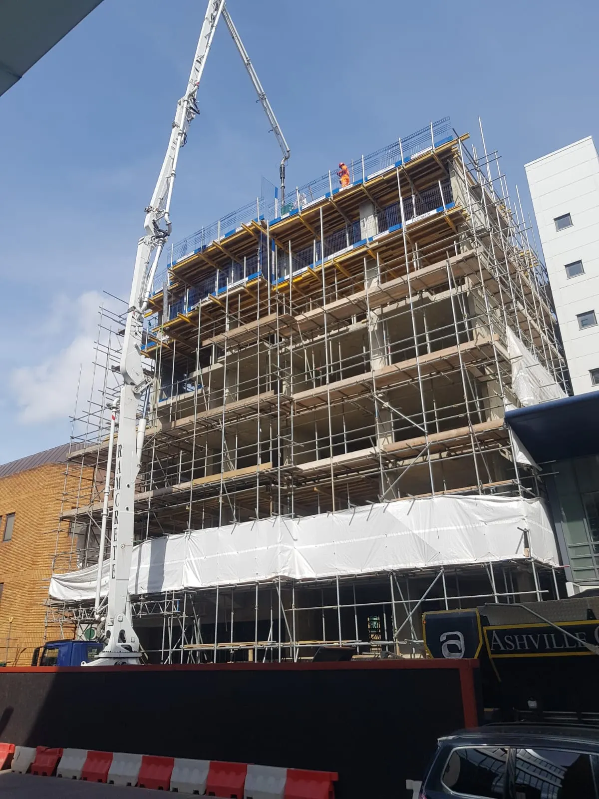 Reinforced concrete frame under construction with a concrete pump boom placing concrete on the top deck